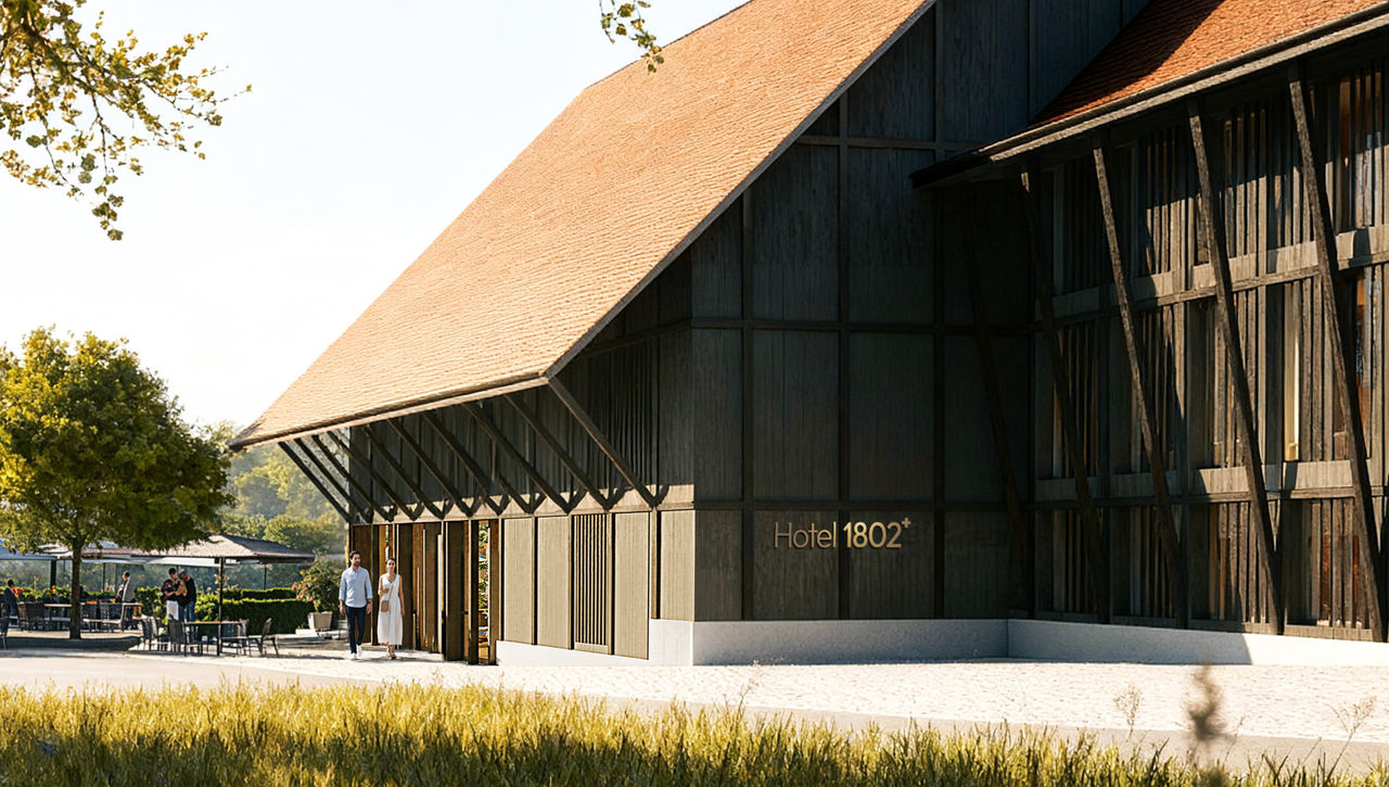 Exterior of Hotel 1802+, a modern barn-style building with dark timber walls and a pitched roof, set in a rural landscape. Guests walk toward the entrance, with an outdoor terrace and trees nearby.