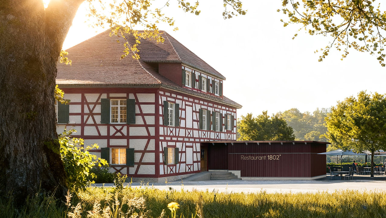 Exterior of Restaurant 1802+, featuring a historic half-timbered building beside a modern extension. The restaurant is set in a green countryside setting with trees, outdoor seating, and warm sunlight.